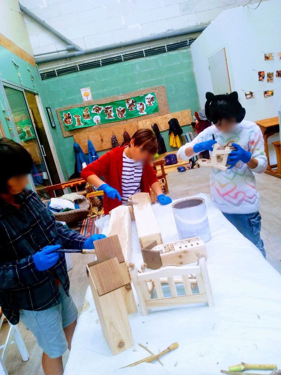 Trois enfants participent à un atelier de bricolage autour de constructions en bois