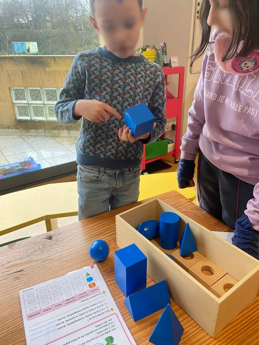 Deux enfants utilisent des solides géométriques bleus en classe