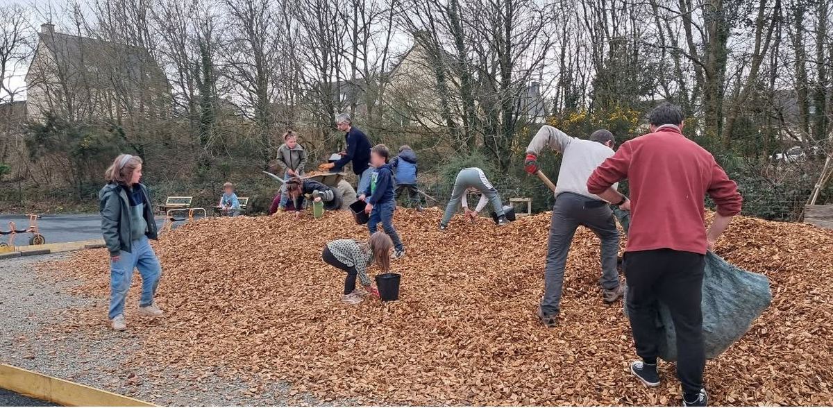 Parents, bénévoles et enfants participent à un chantier collectif dans la cour de l’école